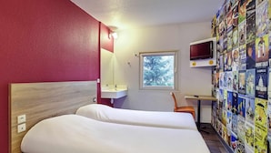 A hotel room with a bed, a small desk with a TV, a window, and a wall decorated with travel posters. - Hotelf1 Marseille Plan De Campagne N°1 (Rénové) (Les Pennes-Mirabeau)