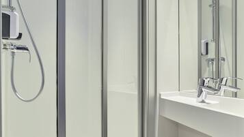 Un baño moderno con cabina de ducha de vidrio, un lavabo blanco y un espejo.