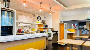A restaurant interior with a counter, seating area, and a menu display. - Ibis Budget Roye (Roye)