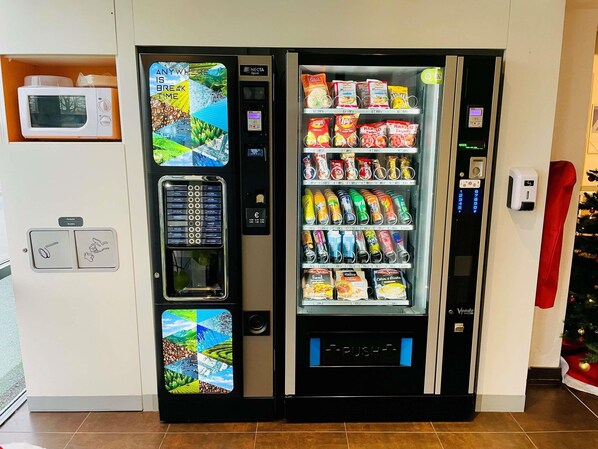 Un distributeur automatique proposant une variété de collations et de boissons, un four à micro-ondes et un terminal de paiement.