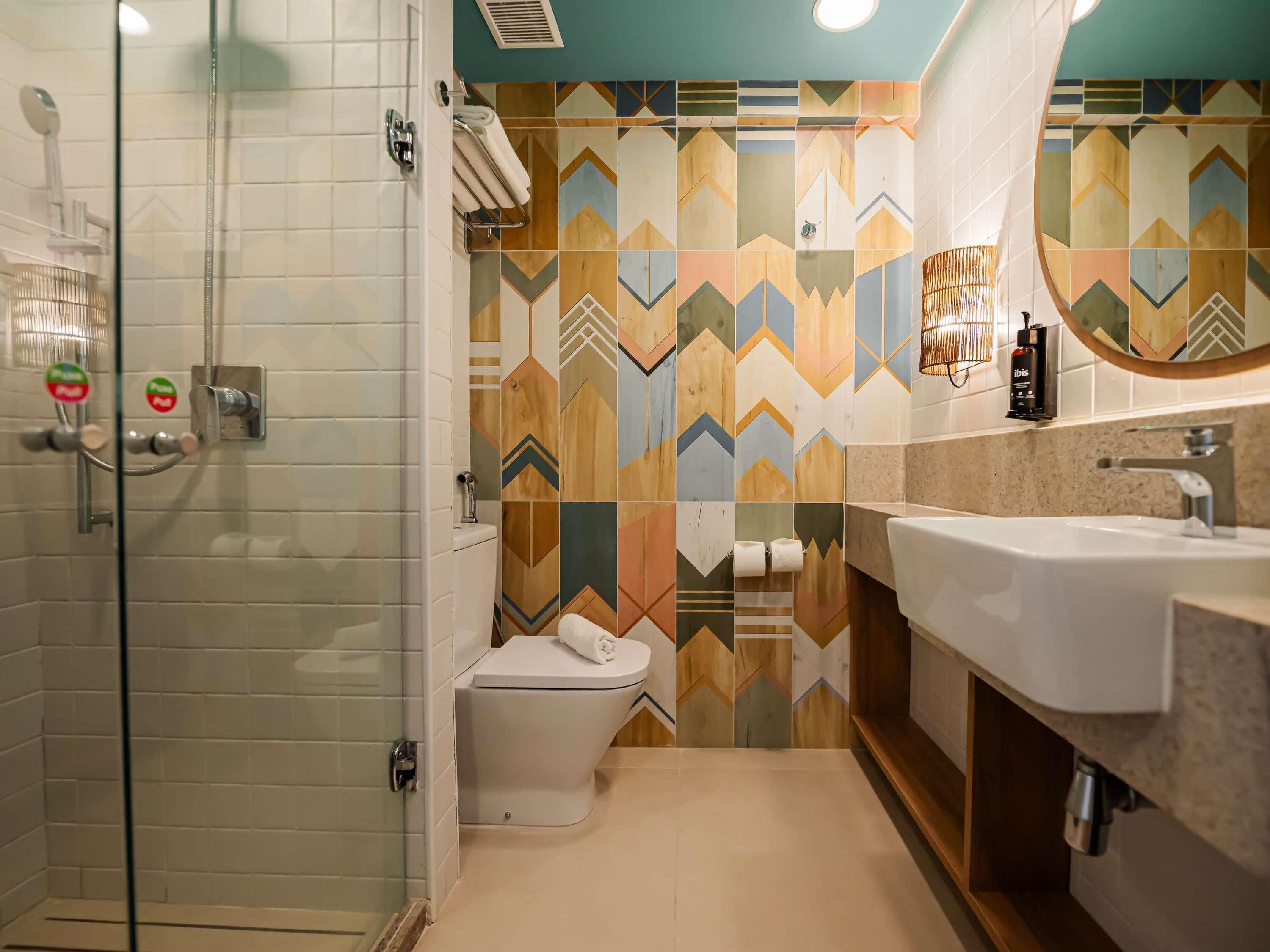Une salle de bain moderne avec une douche à parois de verre, des toilettes et un lavabo surmonté d’un miroir.