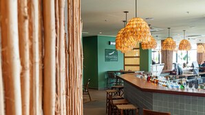 A restaurant interior with bamboo decor, a bar area, and green walls. - Ibis Styles Maragogi (Maragogi)