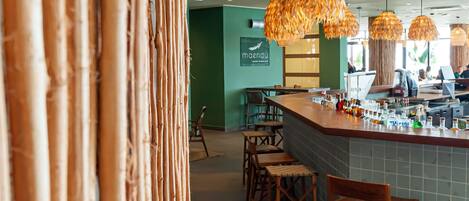Un interior de restaurante con decoración de bambú, una zona de bar y paredes verdes.