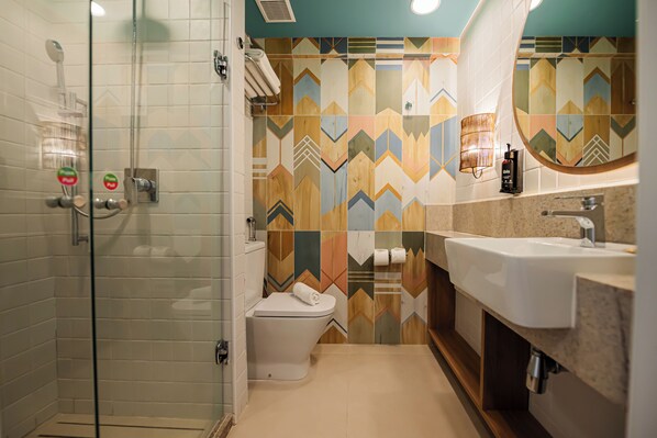 A bathroom with a glass shower enclosure, a toilet, and a sink with a mirror. - Ibis Styles Maragogi (Maragogi)