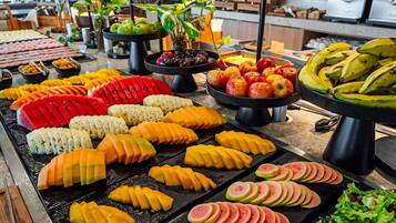 Un bufé con diversas frutas y verduras dispuestas ordenadamente en bandejas.