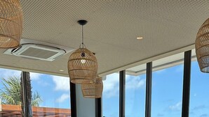 A spacious outdoor seating area with wicker furniture and a view of the beach. - Ibis Styles Maragogi (Maragogi)