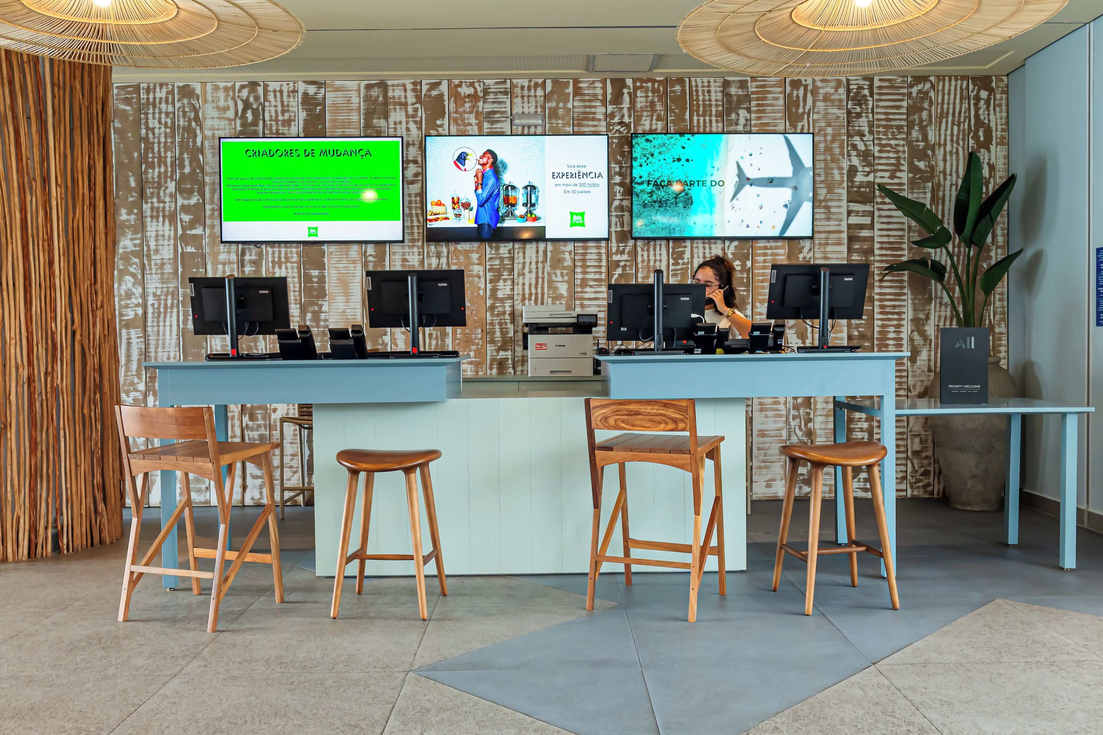 Un'area reception con un bancone, diverse postazioni monitor e sedute in legno.