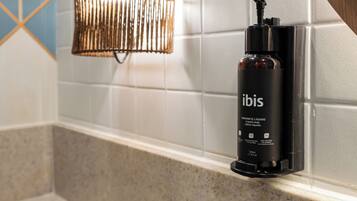 Una botella negra de jabón líquido con la etiqueta 'ibis' sobre una encimera de baño.