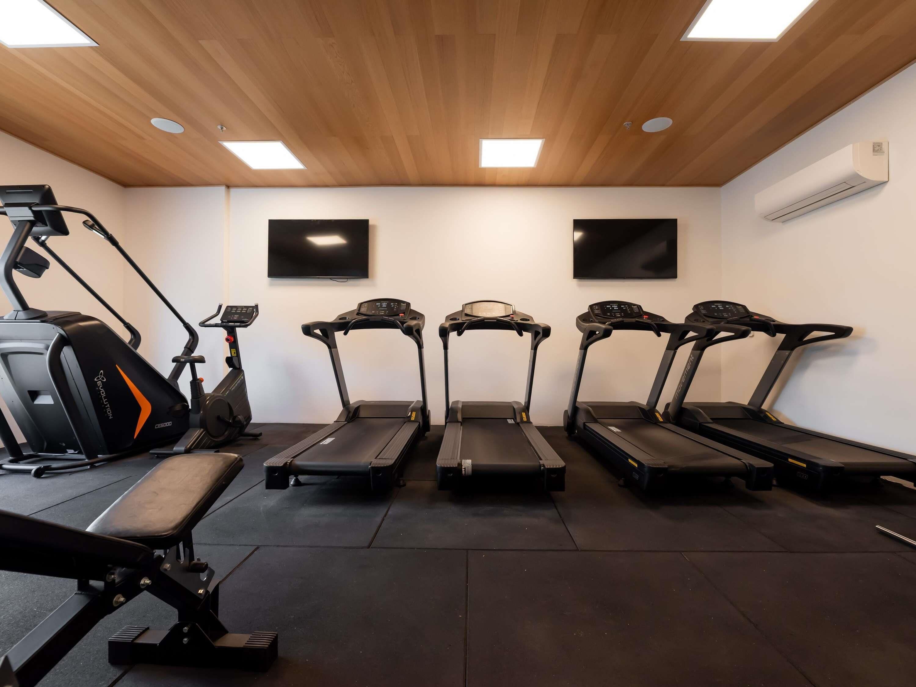 Une salle de sport équipée de tapis de course, d’un vélo d’appartement et d’un banc de musculation.