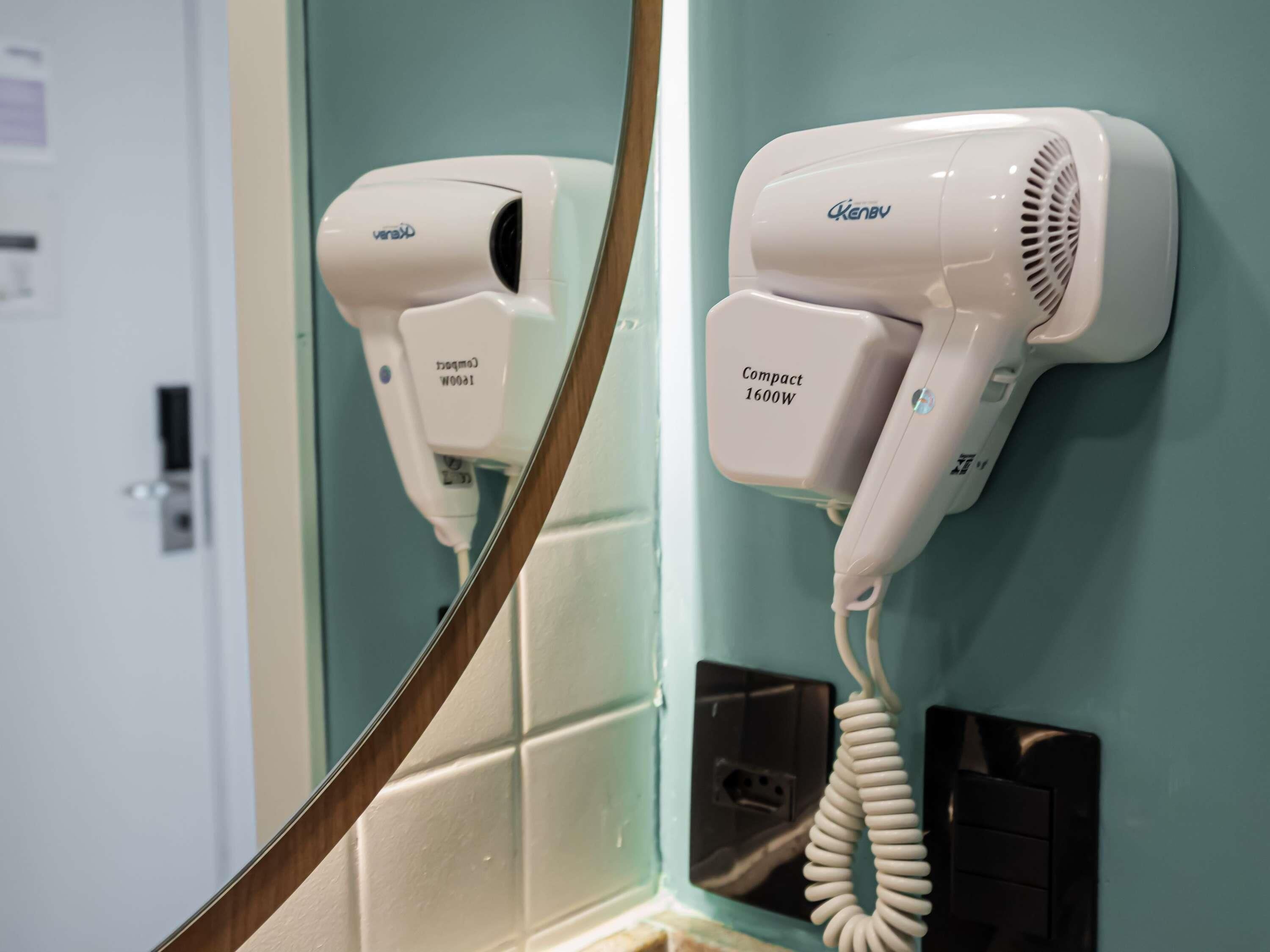 A bathroom with two hair dryers mounted on the wall, one labeled 'Compact 1600W' and the other 'Thermo 1000W'.