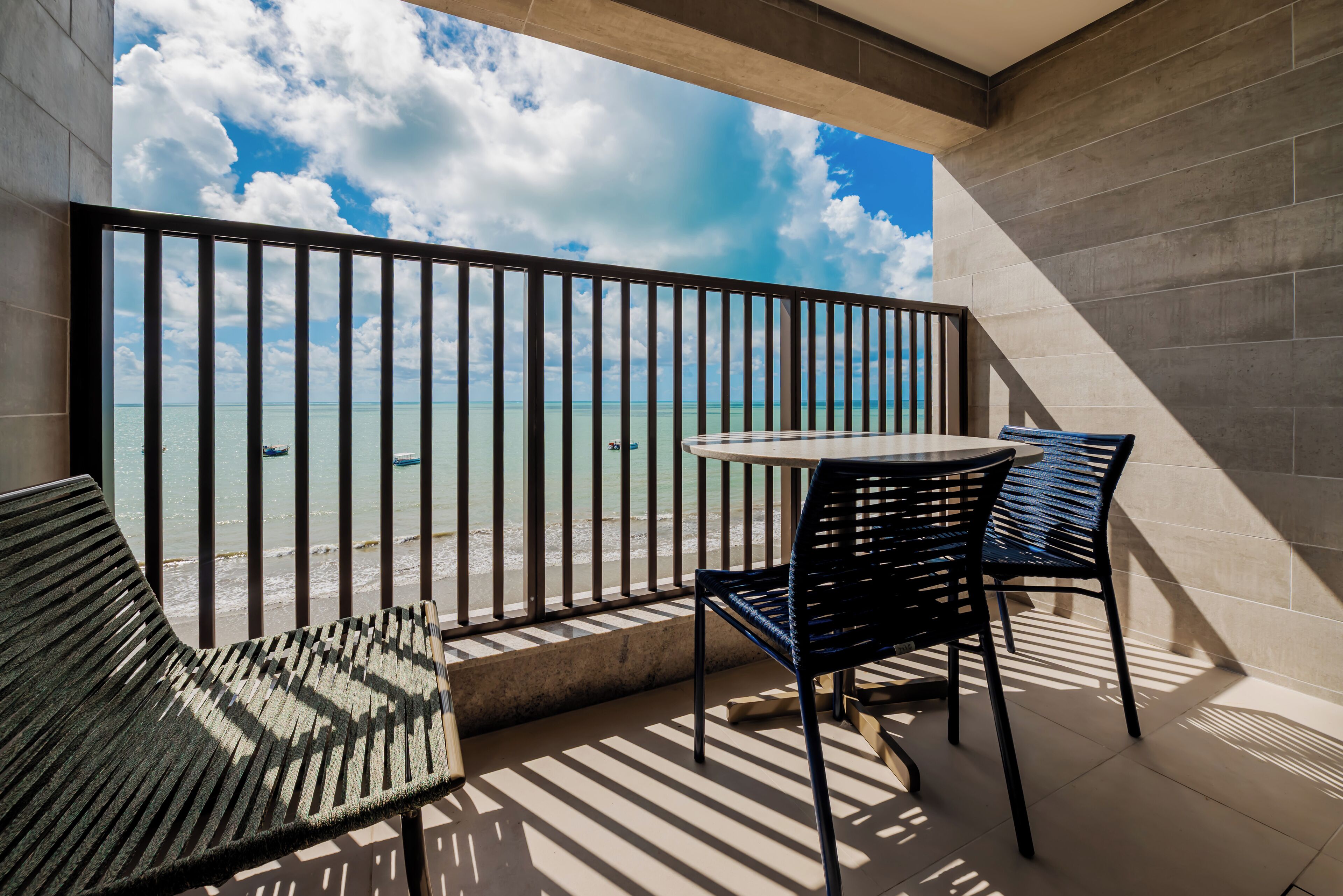 A balcony with a view of the sea, featuring a table and two chairs.