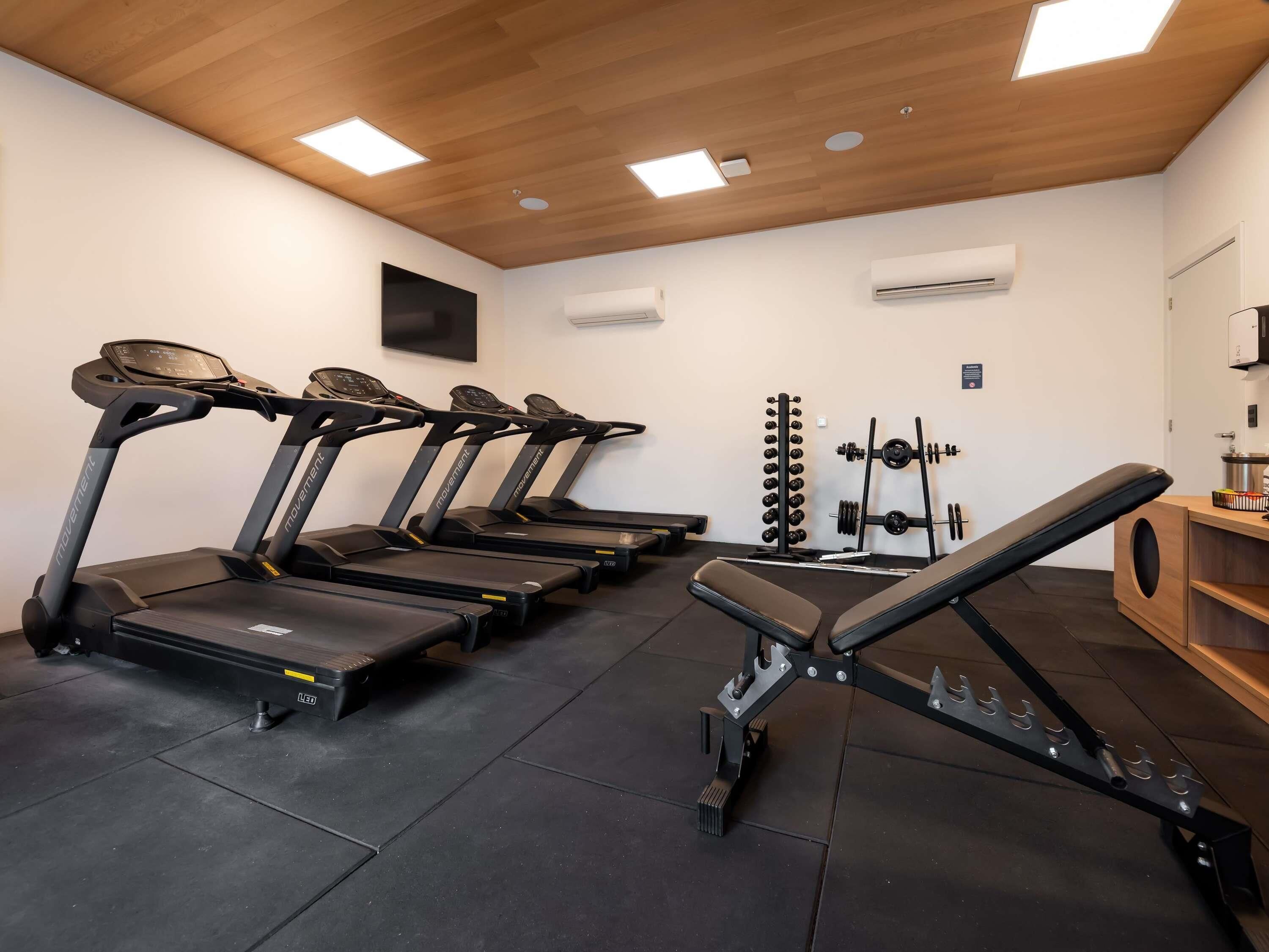 A gym with treadmills, a bench press, and a weight rack.