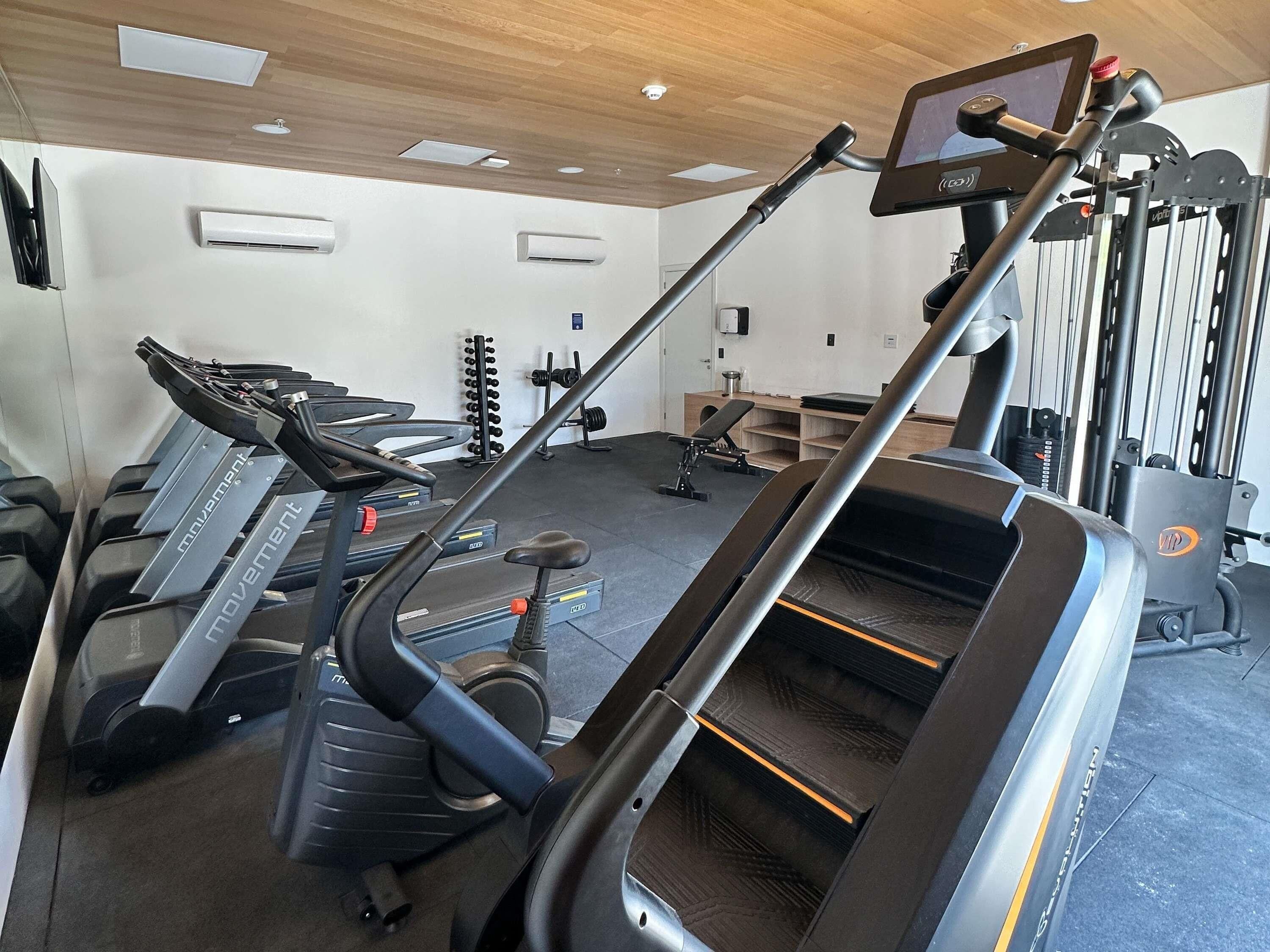 A gym with treadmills, weight machines, and a rowing machine.
