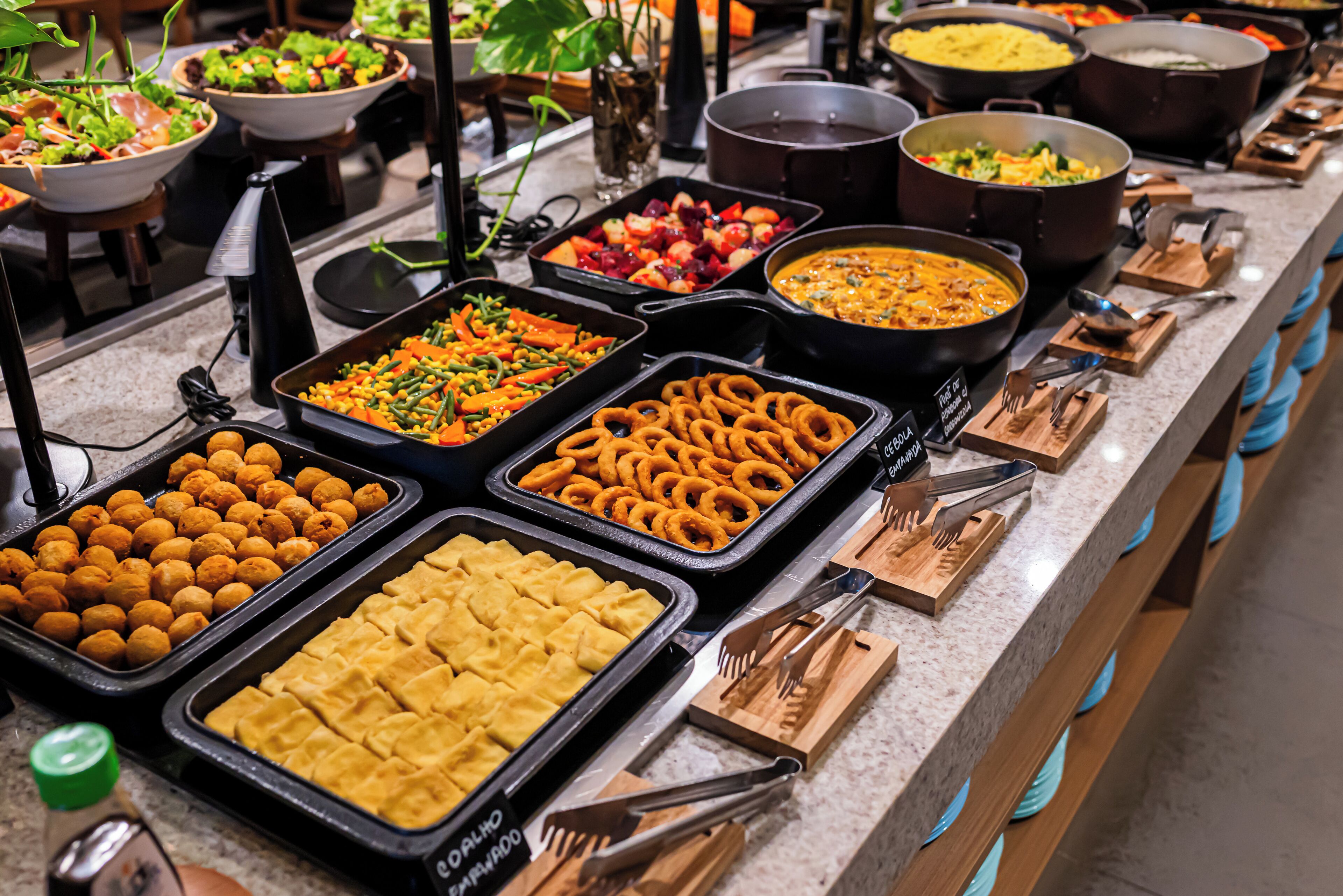 Un buffet proposant une variété de plats, notamment des salades, des fruits et différents types de présentoirs à nourriture.