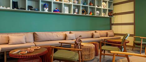 A modern interior with a teal-colored wall, a beige sofa, wooden furniture, and a display of various pottery and decorative items.