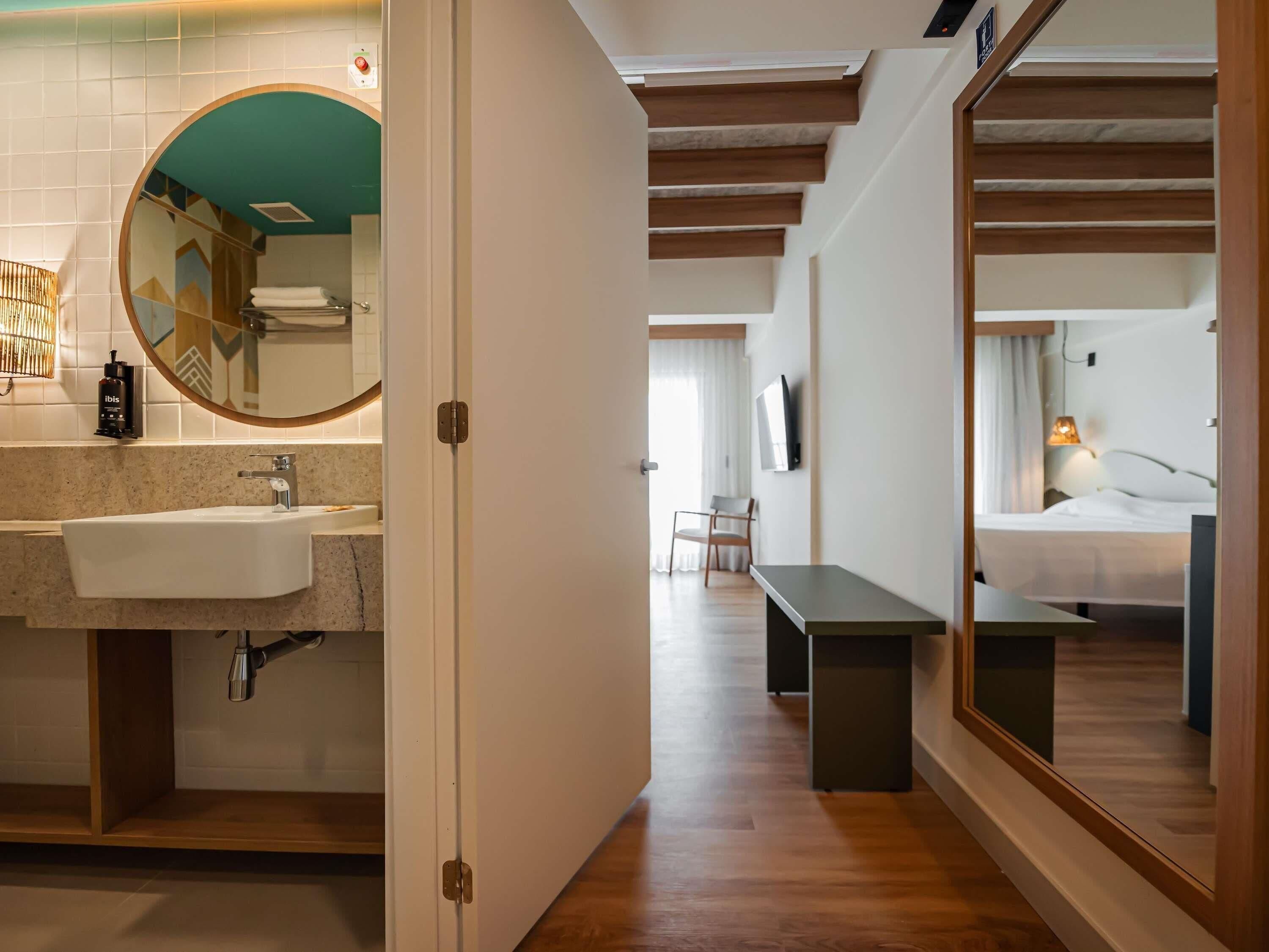 A hotel room with a bathroom, a bed, and a TV.