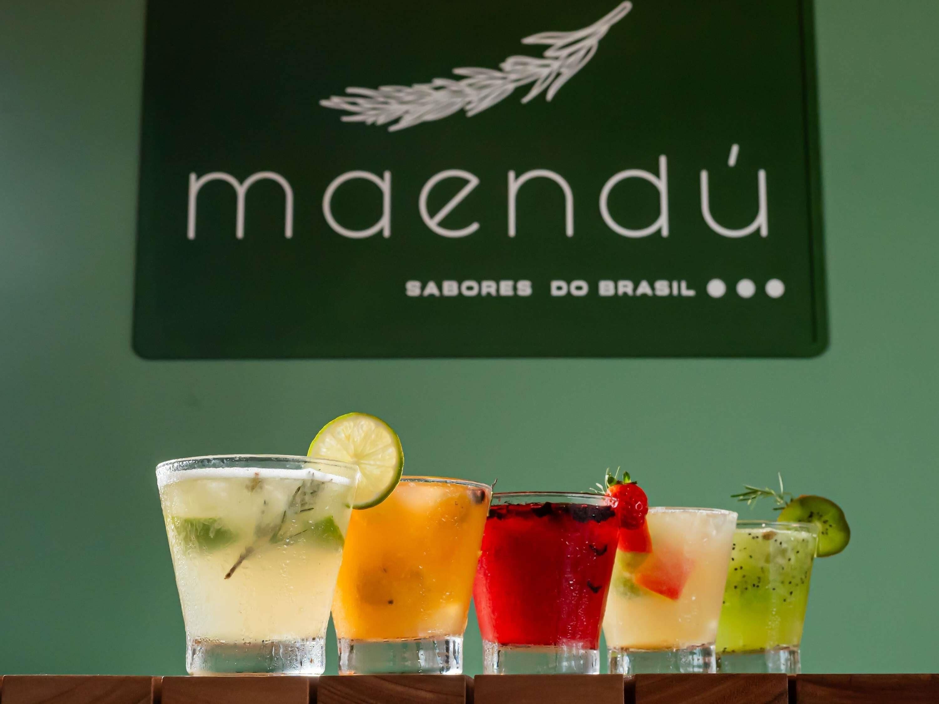 Una zona de bar con una pared verde y un letrero que dice 'maendü SABORES DO BRASIL'.