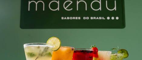 Una zona de bar con una pared verde y un letrero que dice 'maendü SABORES DO BRASIL'.