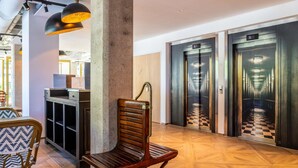 A lobby with a wooden bench, a checkered floor, and two elevators. - ibis Styles Paris Porte de Pantin Philharmonie (Pantin)