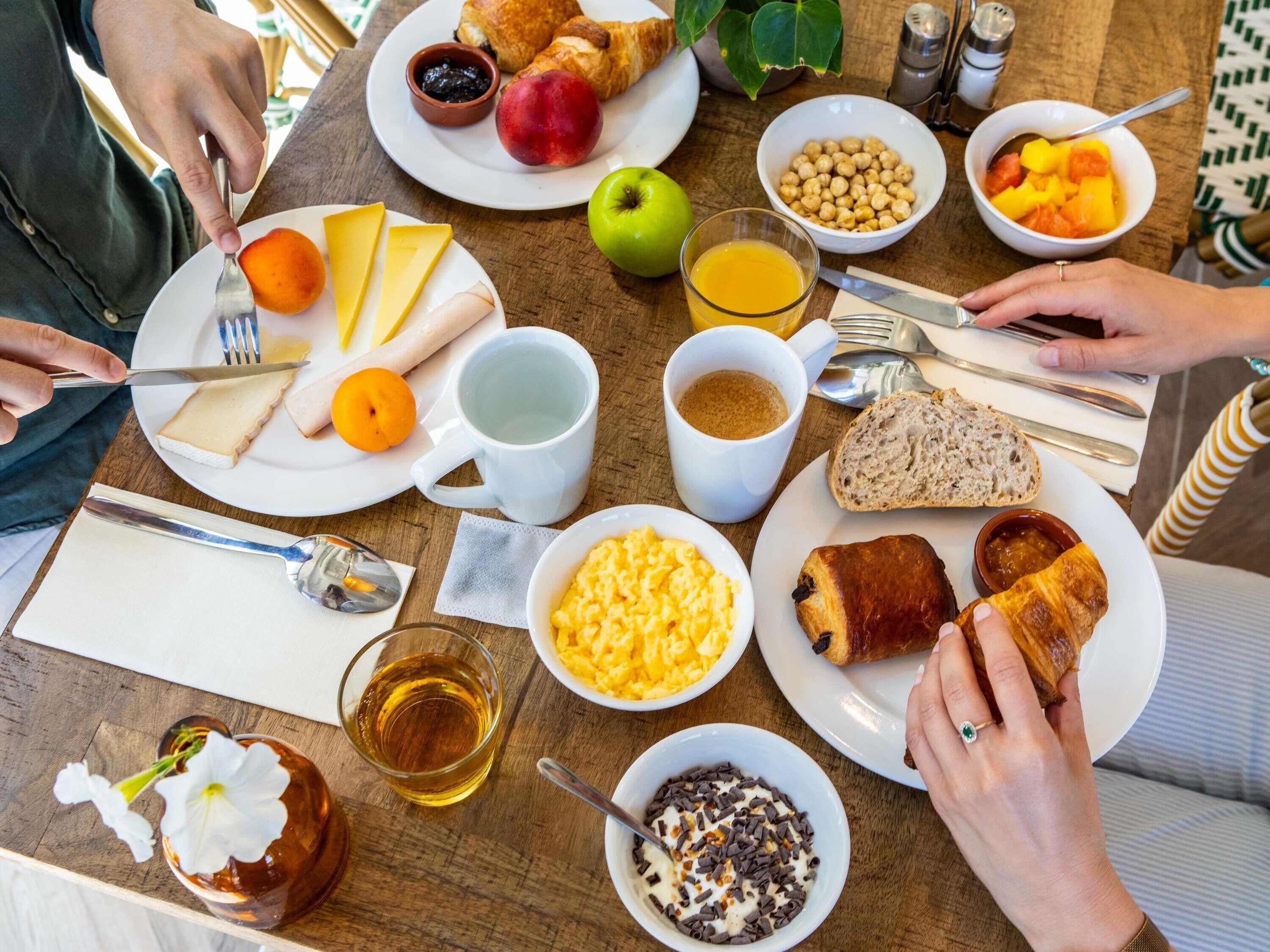 En frukostuppdukning med olika sorters mat och dryck på ett träbord.