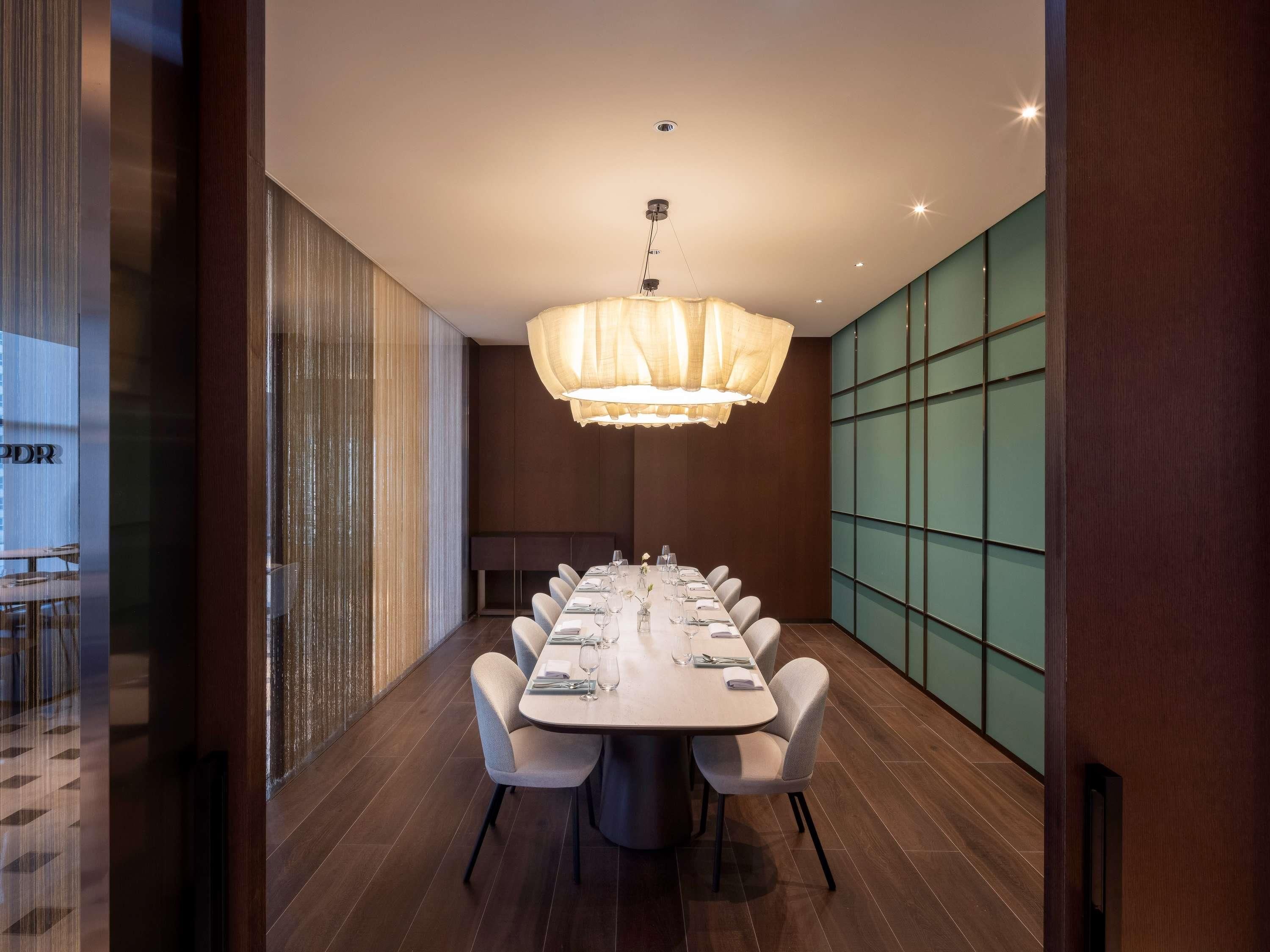 A modern conference room with a long table, chairs, and a chandelier.