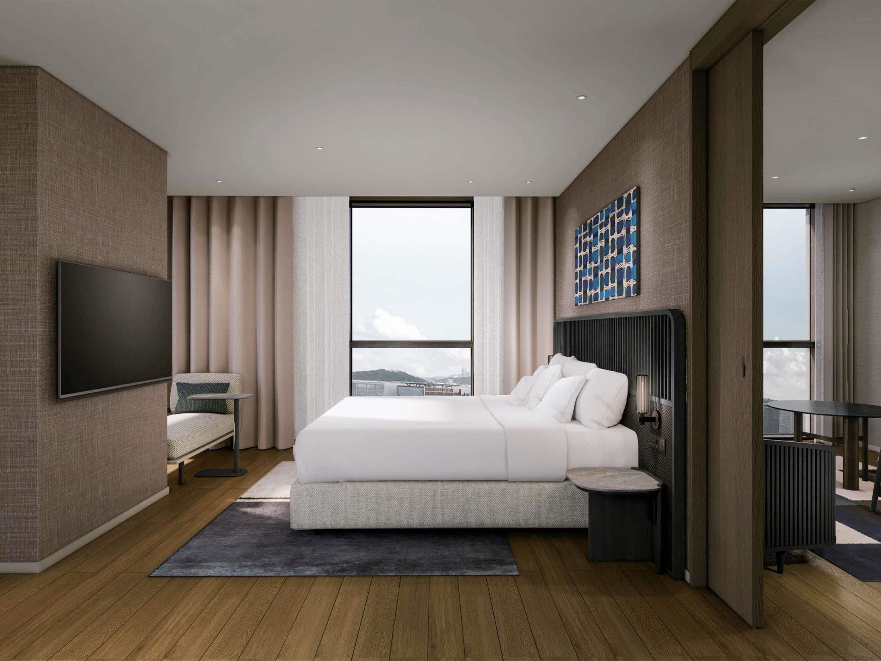 Una habitación de hotel moderna con una cama grande, un televisor de pantalla plana, vistas a la ciudad y una mesita.