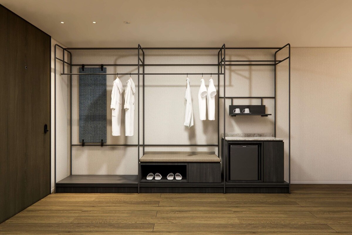 Een moderne kamer met een inbouwkleerkast, een bankje en een klein kastje.