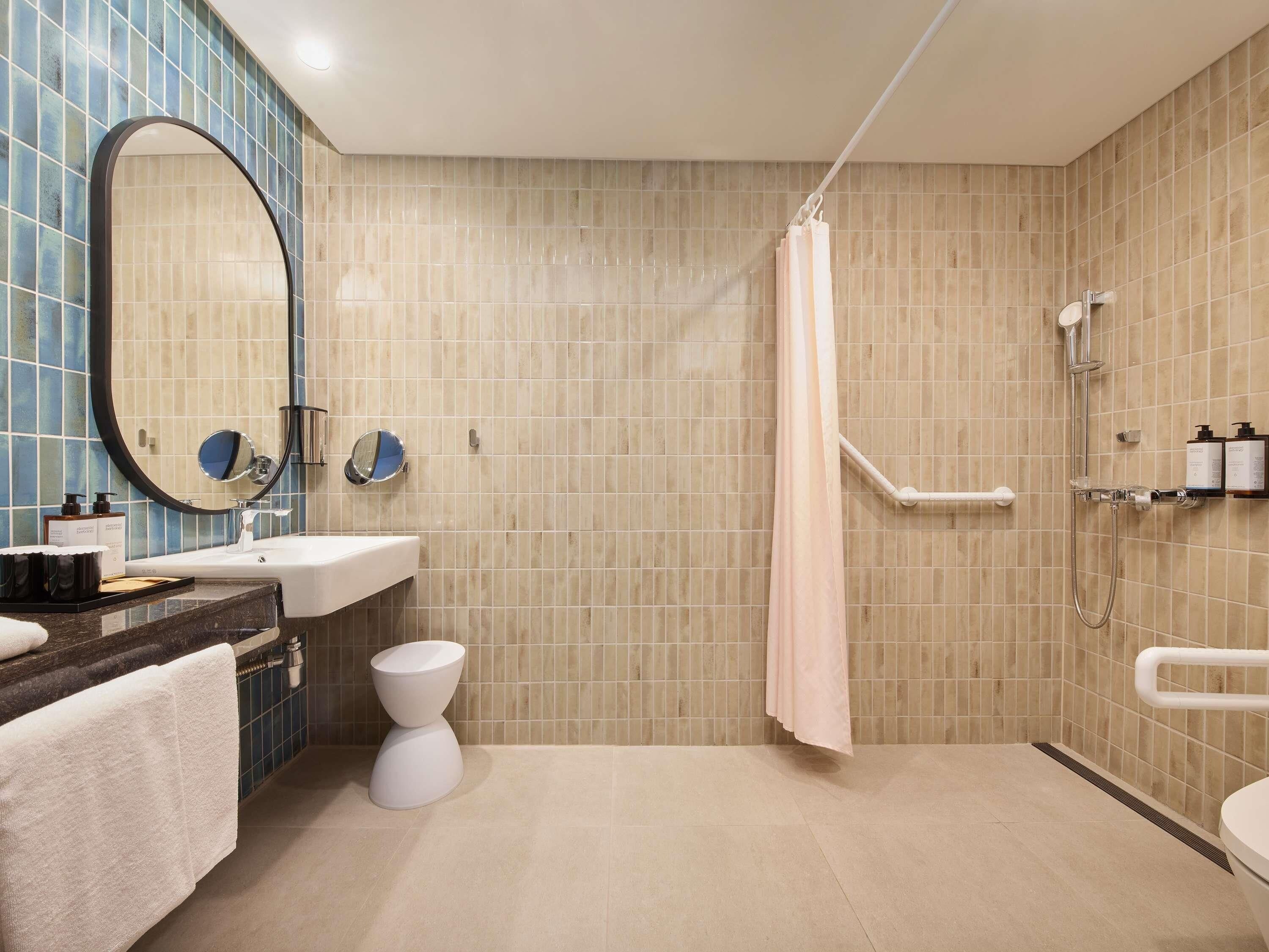 Ein modernes Badezimmer mit Dusche, Waschbecken, Toilette und Spiegel.
