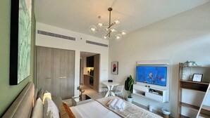 A modern hotel room with a large bed, a TV, a dining area, and a kitchenette. - Waves - Ideal Dubai Retreat Elegant St (Dubai)