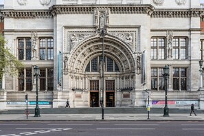 Un imposant bâtiment doté d’une entrée centrale en arc de cercle, flanqué de statues et de colonnes, et d’une enseigne indiquant le musée Victoria and Albert.