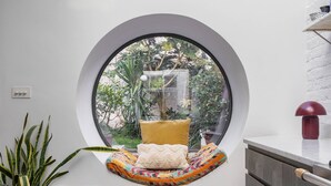 A room with a skylight, a circular window, a bed with pillows, a potted plant, and a cabinet. - Colville Terrace IV by Onefinestay (London)