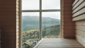 A room with a large window offering a view of a forested mountain range. - Amazing ski in/ski out Chalet in Åre - Övre Sadelvägen Ski Lodge   (Jämtlands län)