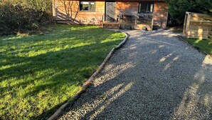 Una cabaña de madera con un camino de grava que conduce a una terraza de madera.