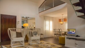 Una sala de estar con muebles de mimbre, un televisor y una escalera.