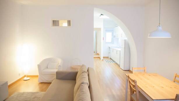 A modern living room with a sofa, a dining table, and a kitchen in the background. - CASA DO COLÉGIO 57 by Azores HomeMade (Ponta Delgada)
