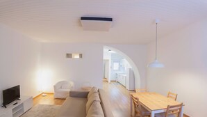 A modern living room with a sofa, TV, and dining table. - CASA DO COLÉGIO 57 by Azores HomeMade (Ponta Delgada)