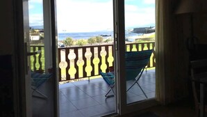 Ein Balkon mit Blick aufs Meer, einem Stuhl und einem gefliesten Boden.