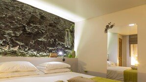 Ett hotellrum med en säng, kuddar, ett väggmonterat akvarium och en spegel som reflekterar en del av rummet.