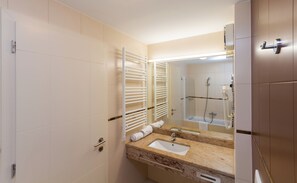 A modern bathroom with two sinks, a large mirror, towel racks, and a shower area.