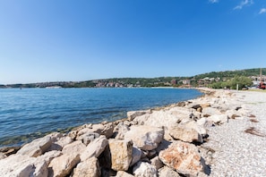A rocky shoreline with a clear view of the sea and a distant town.