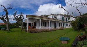 A two-story house with a covered porch and a well-maintained lawn. - QUINTA DAS BOLAS by Azores HomeMade (Ponta Delgada)