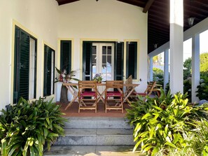 A covered outdoor seating area with a table and chairs, surrounded by greenery. - QUINTA DAS BOLAS by Azores HomeMade (Ponta Delgada)