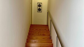 Un escalier en bois avec une rampe métallique, menant à une porte située en haut.