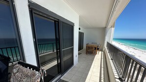 Un balcon avec vue sur la plage, une table à manger et une chaise à motifs.
