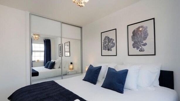 Un dormitorio moderno con una cama grande, un espejo y dos cuadros en la pared.