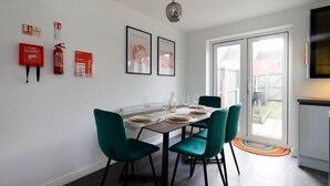 Un comedor con una mesa dispuesta para cuatro personas, sillas color turquesa y un cartel de seguridad contra incendios en la pared.