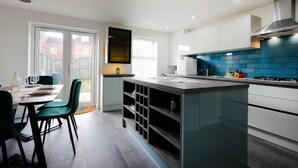 Una cocina moderna con armarios blancos, salpicadero azul y una isla central.