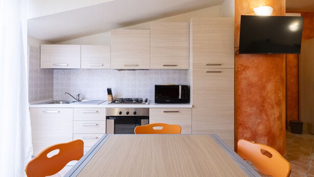 A modern kitchen with white cabinets, a microwave, a stove, and a TV mounted on a column. - Relax in Loano With Terrace by Wonderful Italy (Loano)