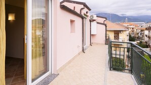 A residential building with a balcony, a sliding glass door, and a view of neighboring houses and mountains. - Relax in Loano With Terrace by Wonderful Italy (Loano)