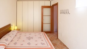 A bedroom with a bed, a wardrobe, a door, and a wall-mounted hook. - Relax in Loano With Terrace by Wonderful Italy (Loano)